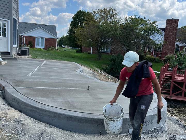 Crew member carrying a bucket across a fresh slab