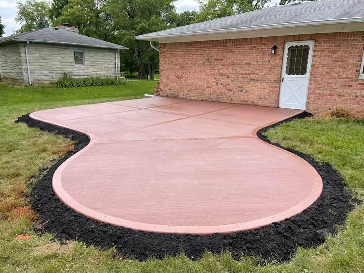 Kidney shaped colored patio at a brick ranch
