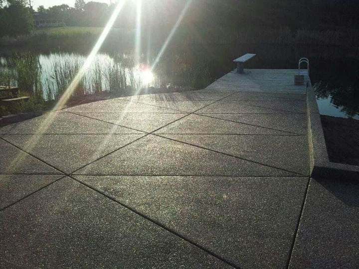 Exposed aggregate pool deck overlooking water at sunset